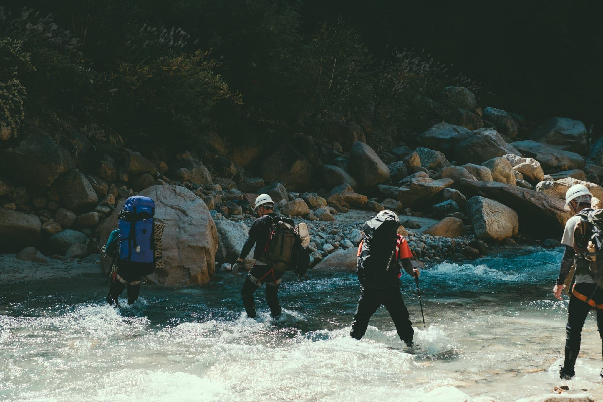 湯俣川の渡渉 — ヘルメットを着用し隊列を組んで急流を渡る