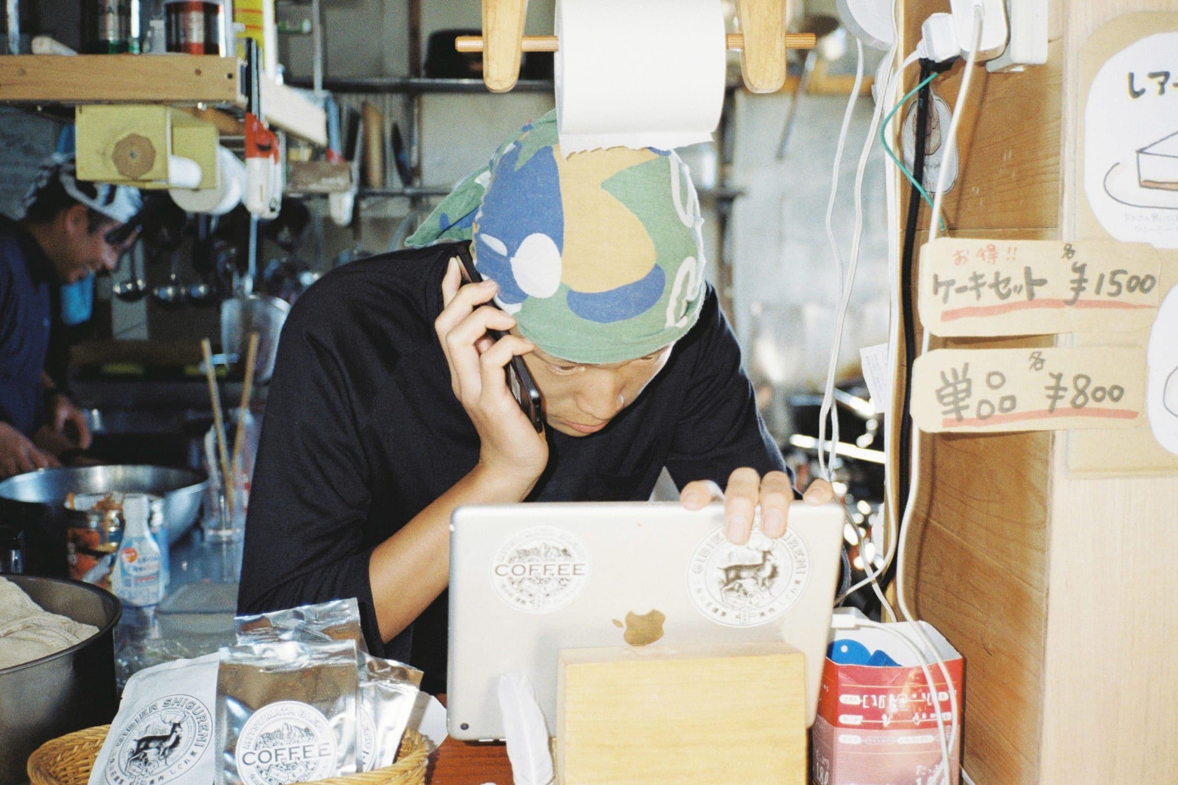 厨房でPCと電話で業務をするスタッフ