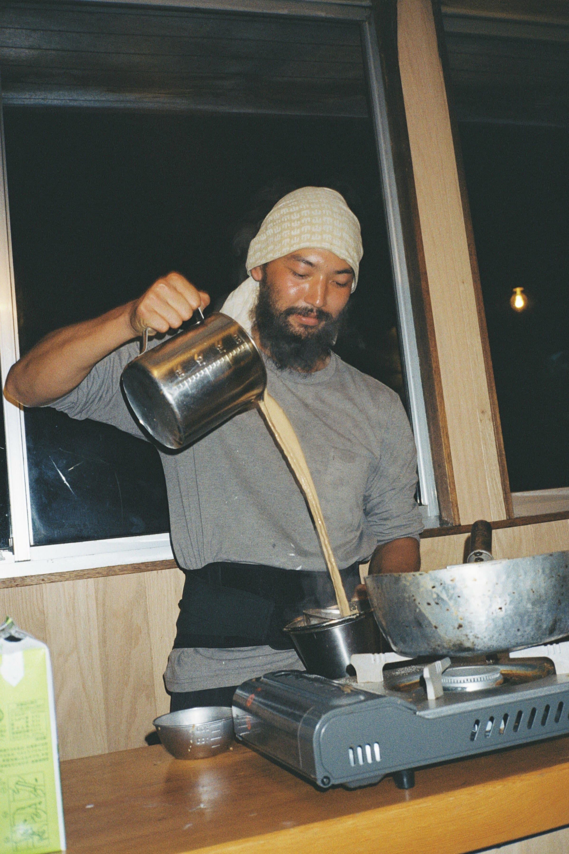 鍋から注ぐ調理中のスタッフ