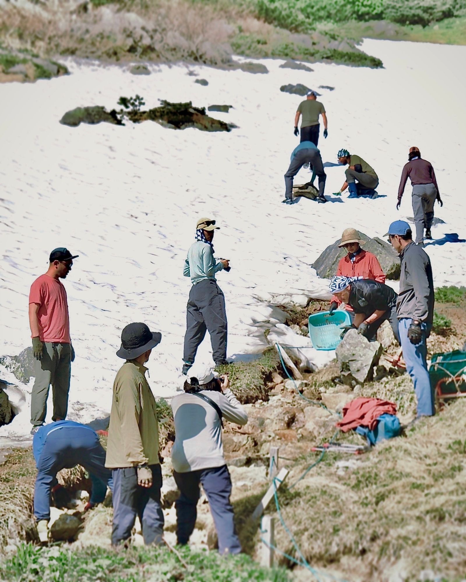 雪渓の残る斜面で作業するアウトドア業界関係者たち